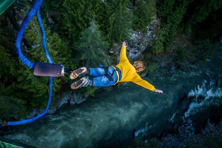 person bungee jumping over a river