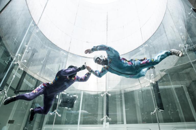 two people in skydiving gear in a simulation lab